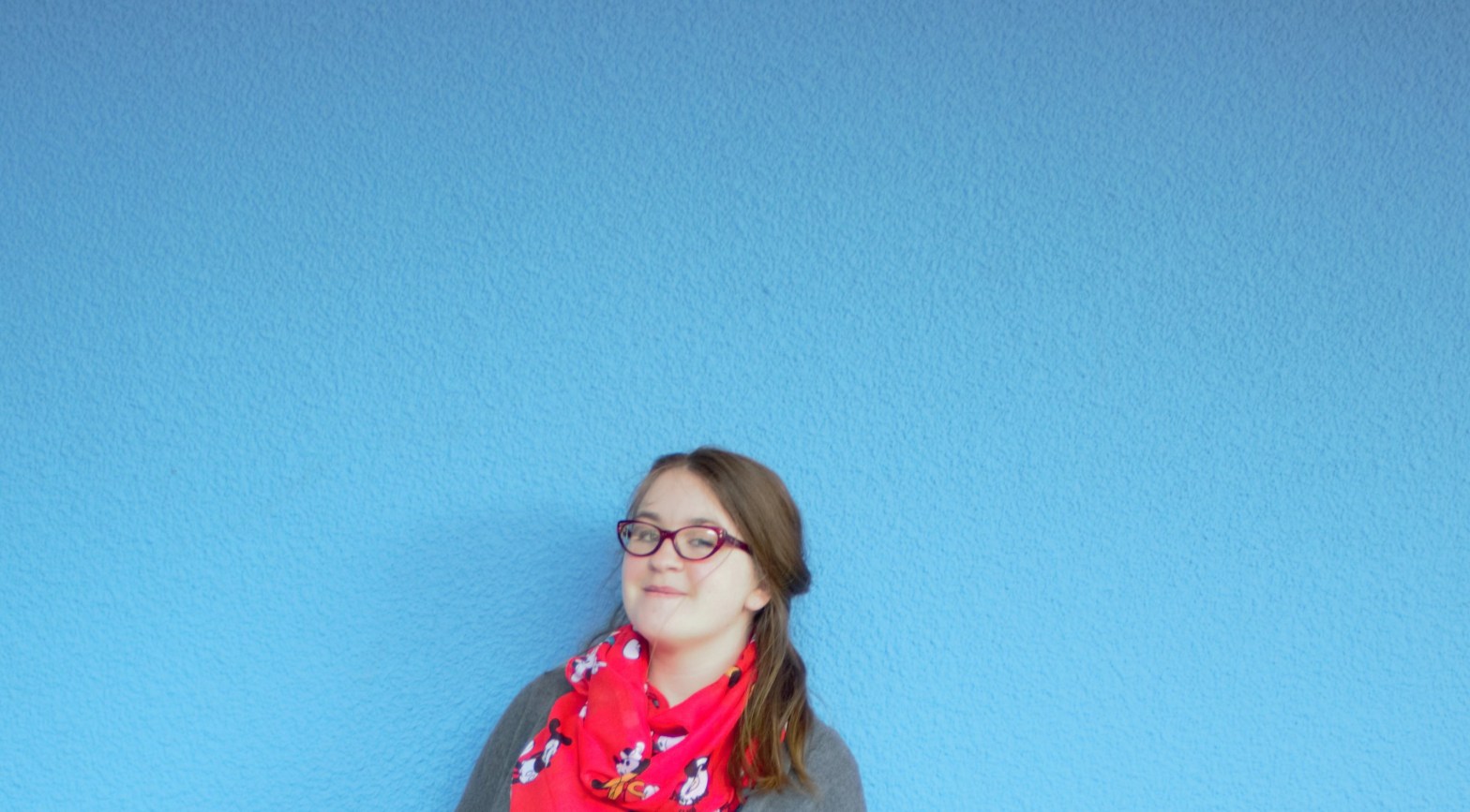 Amy from the shoulders up against the Blue Wall at Disneyland